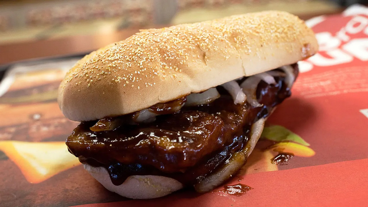 A McRib sandwich served on a table with family enjoying a picnic.